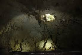 Seen from a cave floor, ropes lower figures down a shaft of light into the cave.